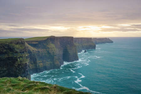 Iconic Cliffs of Moher in Wild Atlantic Way with beautiful dramatic sunset and waves on turquoise oceanの写真素材