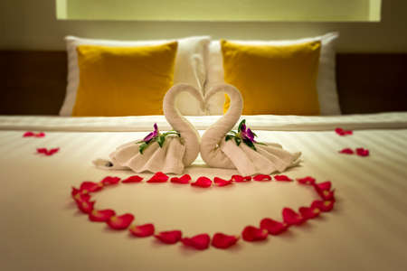 White two towel swans and red rose petals on the bed, Honeymoon decorationの写真素材