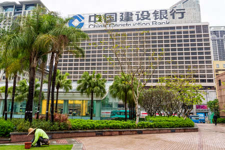 Chinese gardener at work in front of China Construction Bankのeditorial素材