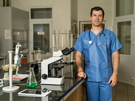 Middle age, Caucasian white, male laboratory technician in blue scrubs with stethoscope standing...