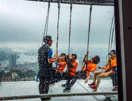 Macau, China, March 2013: Group of people on Sky Walk at Macau Tower in rainy day, popular extreme sport attraction and adrenaline rush activityのeditorial素材