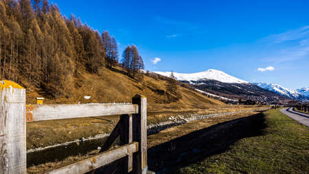Beautiful mountain valley with stream, trees, wooden fence and footpath, Livingo village in background, Italy, Alpsの写真素材