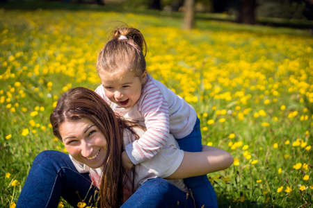 Young little girl and her mom playing on meadowの写真素材