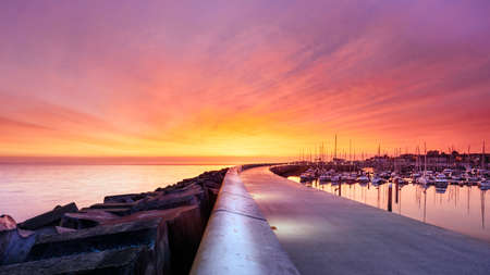 Amazing sky on sunrise at Greystones yacht marina or harbour with anchored boats and long illuminated pier. County Wicklow, Irelandの写真素材
