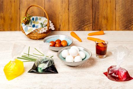 Dying eggs for Easter holiday. White and dyed eggs in decorative bowls and in bags with food colourant nicely arranged on vintage oak wood tableの写真素材