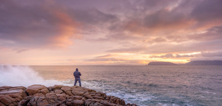 Photographer photographing waves crashing on rocks with amazing sunrise in background. Fanad Head...