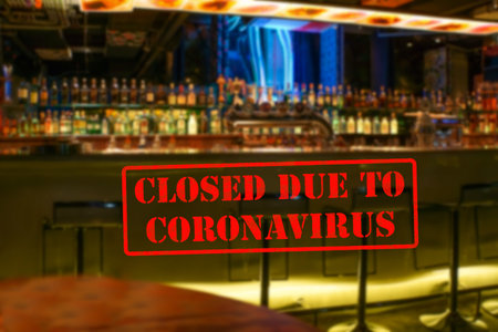 Defocused, blurred view of interior of modern bar or pub, empty and closed due to coronavirus or...