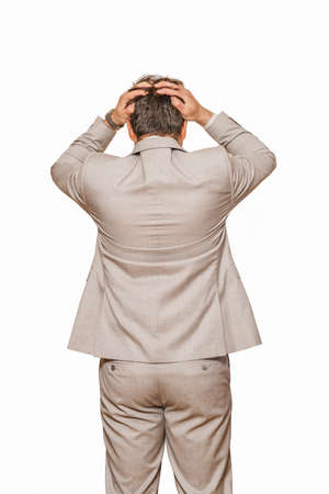 Back view of middle age businessman in beige suite pulling his hair out as his business falling during recession, isolated on white backgroundの写真素材