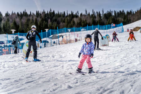 Young happy skier girl learning how to ski on the green ski zone. Young skier having fun on ski slope, Bialka Tatrzanska, Tatry, Polandの写真素材