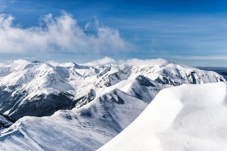 View from Kasprowy Wierch at pine forest with winter coating in the valley. Snow capped mountain...