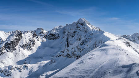View from Kasprowy Wierch on adventurers climbing on Swinica mountain peak at winter. Tatra Mountains range with snow capped mountain peaks, Polandの写真素材