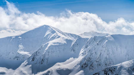 View from Kasprowy Wierch at mountain peak at winter. Amazing mountain range with snow capped mountain peaks in Tatra Mountains, Polandの写真素材