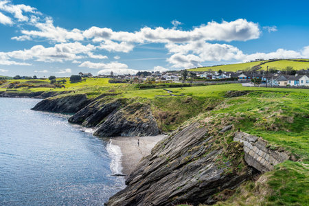 One woman standing on rocky beach between cliffs with old naval fortifications, cannons and Wicklow...