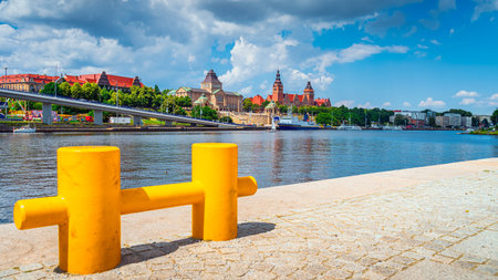 Large, defocused yellow mooring cleat on pier with view on boats, National Museum, Chrobry Shafts and old passport office building in Szczecin, Polandの写真素材