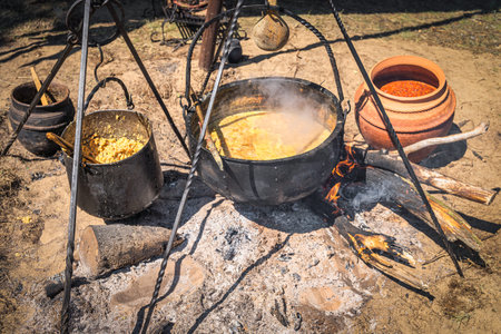 Stew or soup in iron pot or cauldron on a campfire. Homemade food at historical reenactment of...