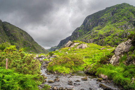 Small lake in beautiful green mountain valley, Gap of Dunloe, with winding road going between steep hills in Black Valley, County Kerry, Irelandの写真素材