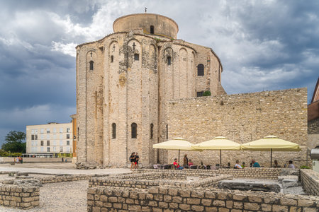 Zadar, Croatia, July 2019 Tourists relaxing in shade of St. Donata, circular church in early...