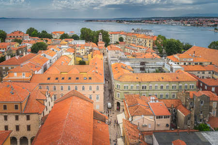 Drone or birds eye view on orange tiled roofs and narrow stone alleys of Zadar old town. Bay and coastline of Adriatic Sea, Croatiaの写真素材