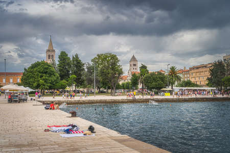 Zadar, Croatia, July 2019 Crowds of tourists walking and relaxing on the Coast of King Petar Kresimir IV. People playing water polo in Adriatic Seaのeditorial素材
