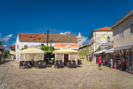 Nin, Croatia, July 2019 Tourists dining in outdoor restaurants and buying souvenir in old district...