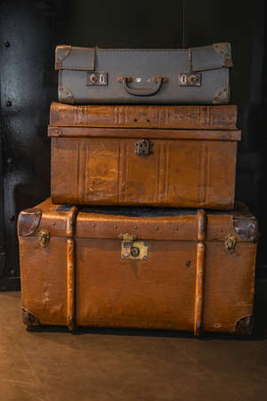 Selective focus on pile of three vintage, old and warn travel suitcases or trunks on the floor. Retro style voyage.の写真素材