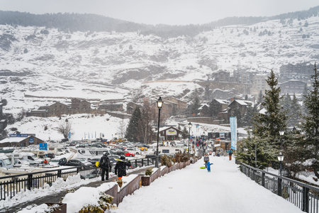 El Tarter, Andorra, Jan 2020 People, families with ski and snowboard equipment walking on main...