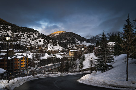 El Tarter village at dusk or night fall with lit street lamps and last sunlight illuminating mountain peak in Pyrenees mountains, Grandvalira, Andorraの写真素材