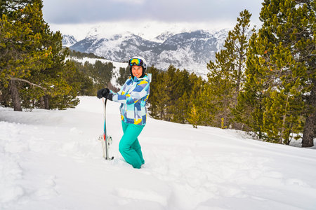Portrait of a woman, skier, standing in deep snow and holding ski, looking at camera. Winter ski holidays in El Tarter, Andorra, Pyrenees Mountainsの写真素材