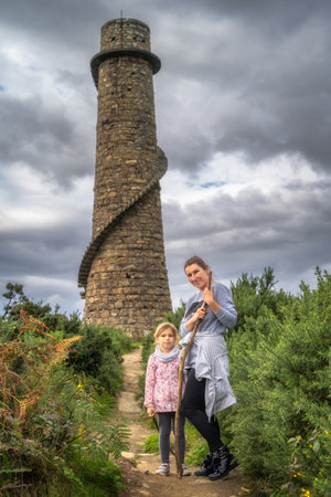 Mother and daughter standing in front of old and abandoned stone chimney with external spiral stairs in Lead Mines, Wicklow Mountains, Irelandの写真素材