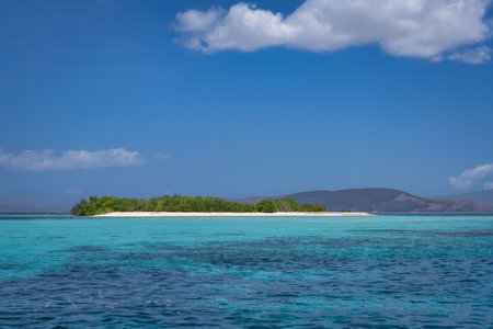Imagine a serene tropical island with sandy beach, lush greenery, clear turquoise waters, and a bright blue sky, ideal for relaxation and exploring natural beauty, Komodo, Indonesiaの写真素材