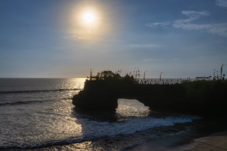 Breathtaking sunset illuminating the ocean waves with a rocky arch silhouette, capturing natures tranquility and beauty next to Tanah Lot Temple, Bali, Indonesiaの写真素材