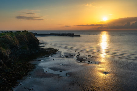 A captivating sunset remarkably illuminating the oceans surface, beautifully casting golden reflections on the peaceful shoreline, creating a breathtaking scene, Loughshinny, Dublin, Irelandの写真素材