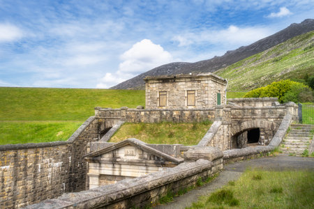 Silent Valley Reservoir stone structure dam stands among rolling green hills and a clear blue sky, creating a captivating scene that enchants with its timeless allure, Newry, Northern Irelandの写真素材