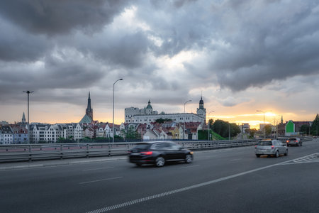 A breathtakingly picturesque city skyline is beautifully illuminated at sunset, showcasing bustling traffic and majestic historic building of Castle of the Pomeranian Dukes, Szczecin, Polandの写真素材