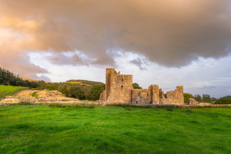 Historic Fore Abbey ruins under soft light. Solitary stone walls on rolling green hills. Quaint heritage site bathed in warm sunset hues amidst lush countryside and dramatic skies, Irelandの写真素材