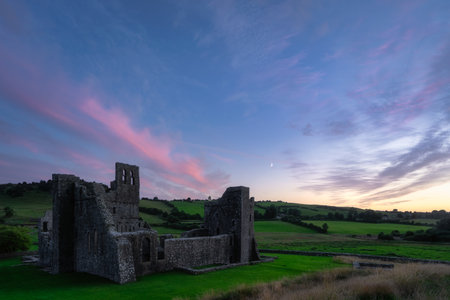 Idyllic Irish scenery with peaceful sunset and historic Fore Abbey ruins. Calm twilight view featuring ancient abbey remains surrounded by soft sunset colors and gentle skies, Irelandの写真素材