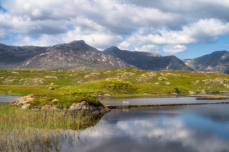 Mountain ridge overlooking reflective marsh next to Pine Island Viewpoint in Connemara, Galway,...