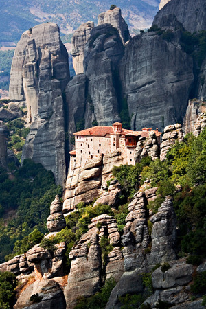 Mountain, remote monastery on the inaccessible rocks in striking sun light on the background of hazy Greek landscape; in Meteora, Greece.の写真素材