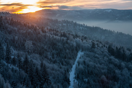 Sunset behind the mountain. Winter season and frozen trees