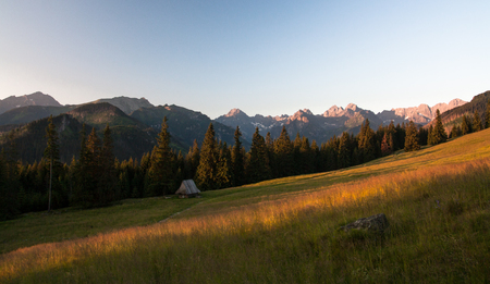 Panorama of the Tatras seen from the glade. Cloudy blue sky in the background and a green meadow in the foregroundの写真素材