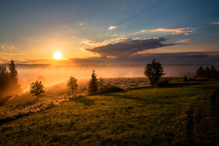 a golden mist hovering over the fields after heavy rains at sunset timeの写真素材