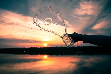 splash of water from the jar. sunset in the background at the lakeの写真素材