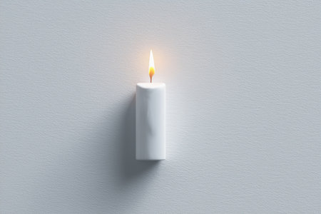 Elegant White Burning Candle with Warm Glowing Flame Centered Against a Clean Textured Gray Backgroundの素材
