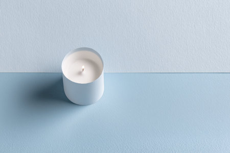 Minimalist White Lit Candle on a Soothing Two-Tone Textured Light Blue Backgroundの素材