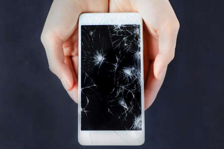Girls hands holding a smart phone with broken screen.の写真素材