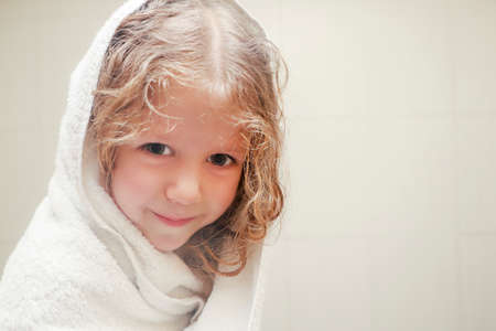 Little curly girl in towel in bathroom after shower, close up.の写真素材