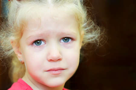 Little crying curly blonde girl portrait. Sad birthday.の写真素材