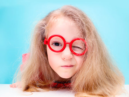 Funny little blonde girl with glasses looking at the camera.の写真素材