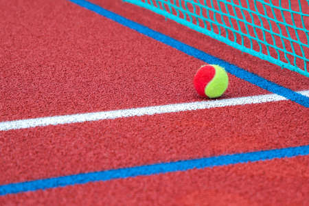 Red tennis court with tennis ball, artificial cover ,close up.の写真素材