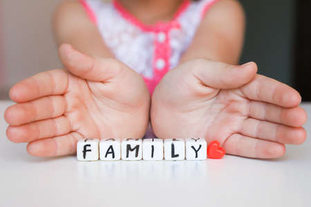 Little girl hold toy blocks with word Family. Protect your family concept. Word Family made of plastic blocks.の写真素材